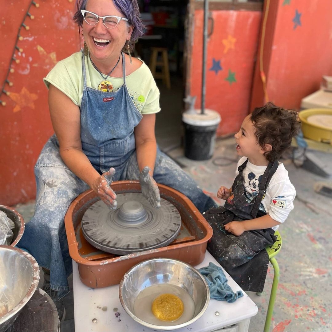 Gretchen with child using a pottery wheel